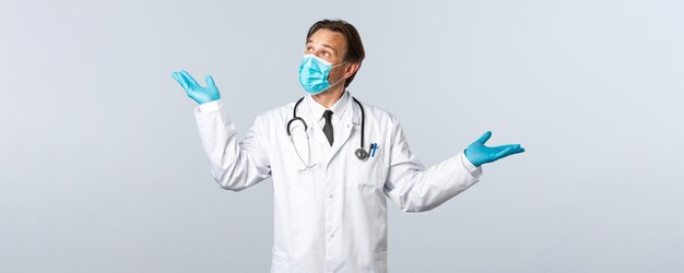 Covid-19, prevención de virus, trabajadores sanitarios y concepto de vacunación. Médico profesional con máscara y guantes presenta el producto, demostrando la medicación, mirando arriba a la izquierda