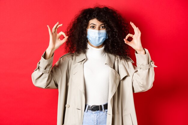 Covid concepto de distanciamiento social y cuarentena mujer de moda con cabello rizado con máscara médica ...