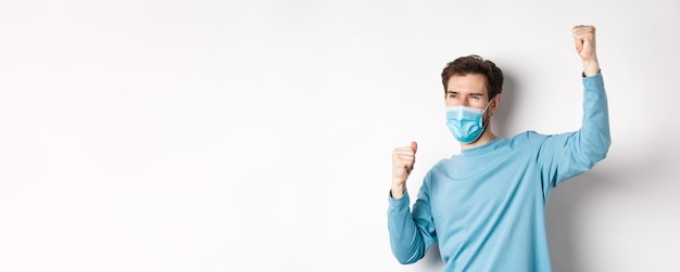 Foto gratuita covid pandemia y concepto de distanciamiento social hombre feliz con máscara médica viendo juegos deportivos y chee