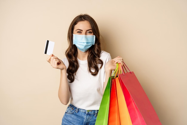 Covid pandemia y concepto de estilo de vida mujer joven posando en mascarilla médica con bolsas de compras de...