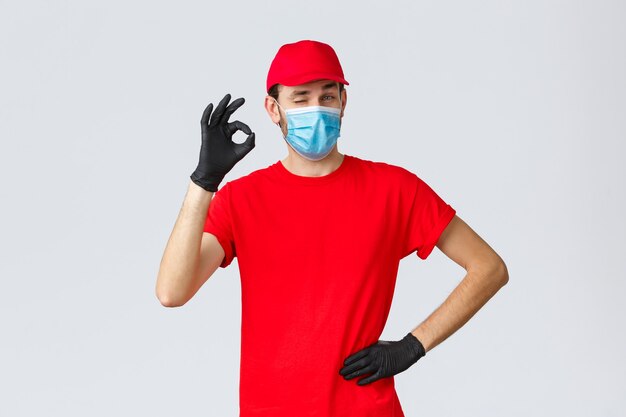 Covid selfquarantine concepto de envío y compras en línea repartidor con gorra de camiseta roja con cara m ...