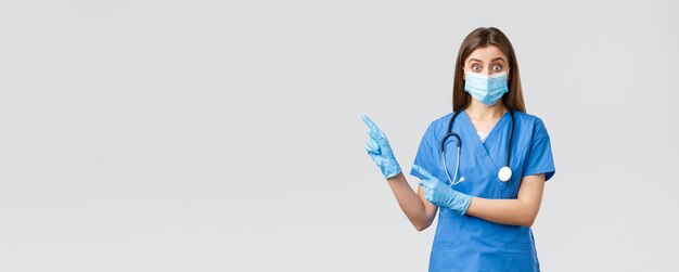 Foto gratuita covid19 prevención de virus salud trabajadores de la salud y concepto de cuarentena doctora interesada y cuestionada enfermera en batas azules y máscara médica haciendo preguntas apuntando a la izquierda