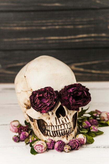 Cráneo humano con rosas en las cuencas de los ojos