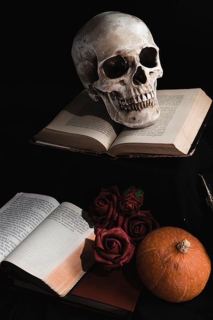 Foto gratuita cráneo en libros con rosas y calabaza