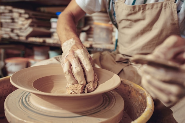 Creación de un primer plano de una jarra o jarrón de arcilla blanca. Maestro olla. Manos de hombre haciendo macro de jarra de arcilla.