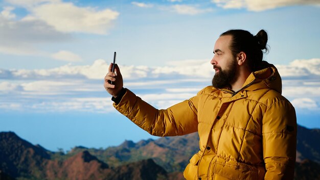 Creador de contenido masculino grabando un video rodeado de picos de montaña