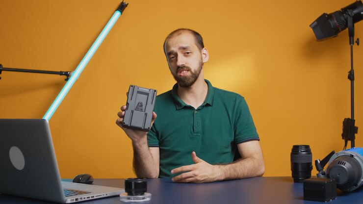 Foto gratuito creador de contenido sosteniendo y grabando revisión de batería de montaje en v para vlog. acumulador profesional. tecnología moderna tipo v-lock, distribución en línea de influencer estrella de las redes sociales