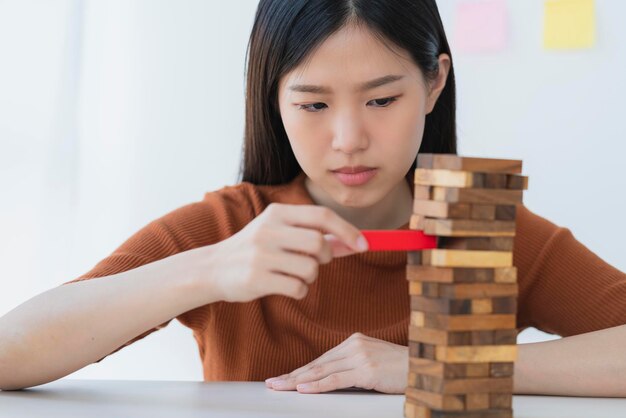 Creatividad empresarial y concepto de ideas de estrategia inteligente hermosa mujer asiática intenta construir una torre de bloques de madera para un fondo blanco estable y exitoso