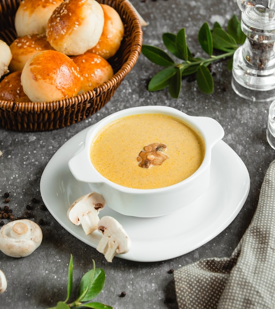 Foto gratuita crema de champiñones con crema y una canasta de pan