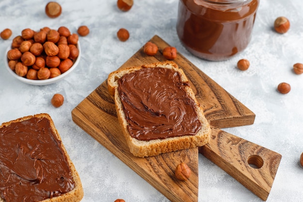 Crema de chocolate o turrón con avellanas en frasco de vidrio sobre hormigón, copyspace