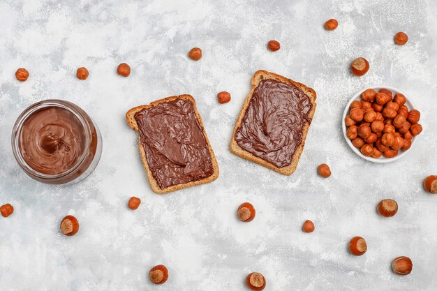 Crema de chocolate o turrón con avellanas en frasco de vidrio sobre hormigón, copyspace