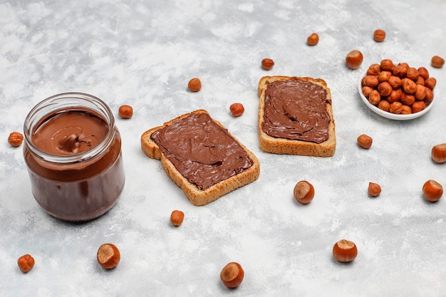 Foto gratuita crema de chocolate o turrón con avellanas en frasco de vidrio sobre hormigón, copyspace