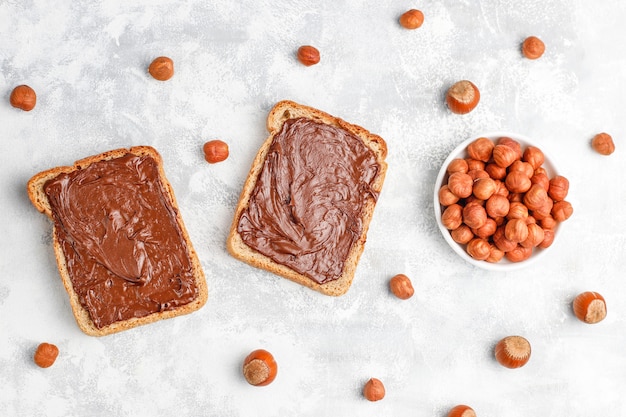 Crema de chocolate o turrón con avellanas en frasco de vidrio sobre hormigón, copyspace