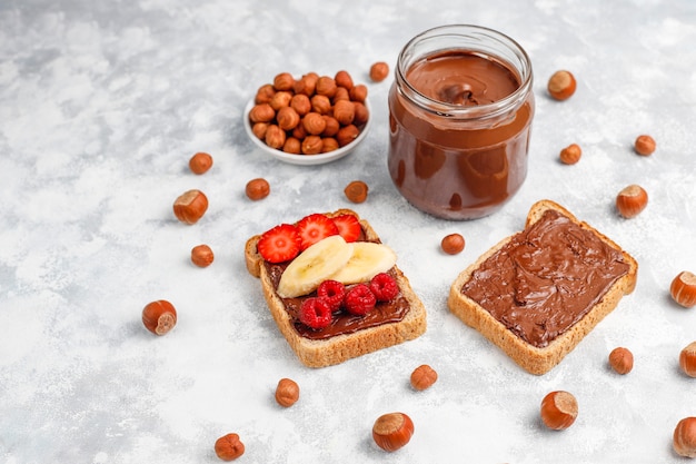 Foto gratuita crema de chocolate o turrón con avellanas en frasco de vidrio sobre hormigón, copyspace