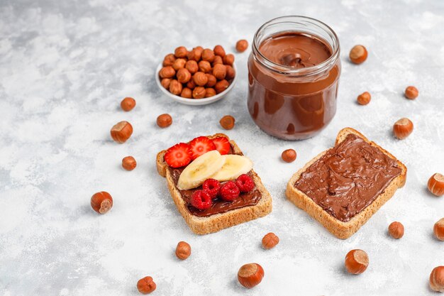 Crema de chocolate o turrón con avellanas en frasco de vidrio sobre hormigón, copyspace