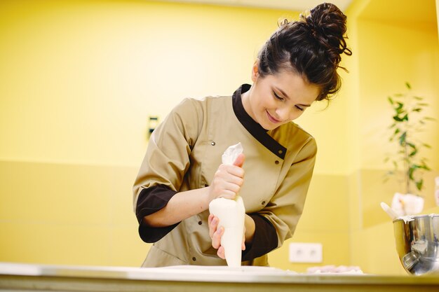 Foto gratuita crema en manga pastelera. señora con una herramienta para hornear.