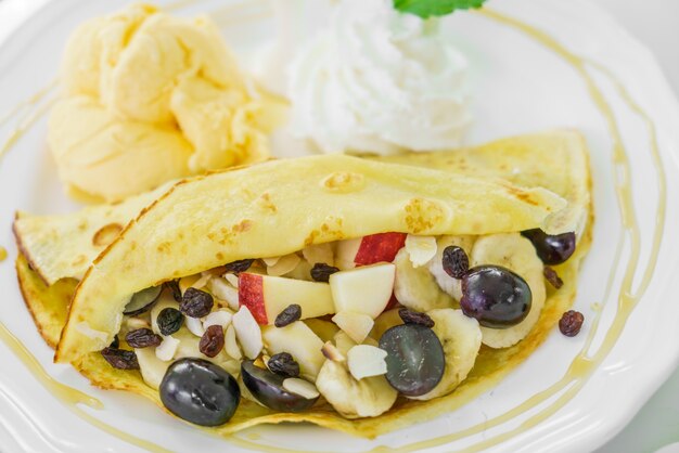 Crepe y las frutas con helado en la mesa