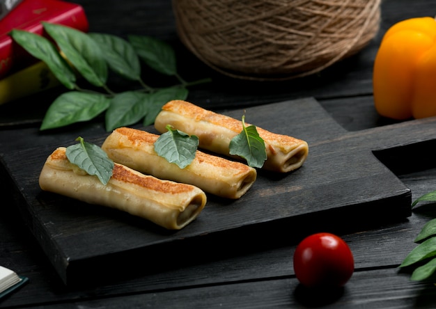 Crepes de blinchik rusos con hojas de orégano y tomate