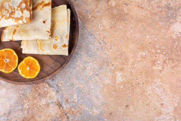 Crepes con rodajas de naranja en bandeja de madera