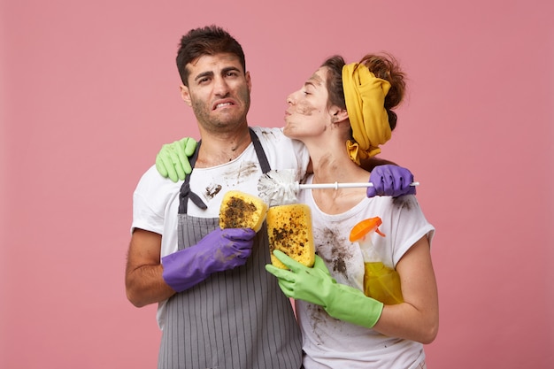 Criada en ropa casual y guantes protectores va a besar a su marido que tiene aspecto cansado y agotado