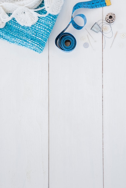 Crochet y tejido de punto; cinta métrica; chincheta; dedal; Hilo y botón en mesa de madera.