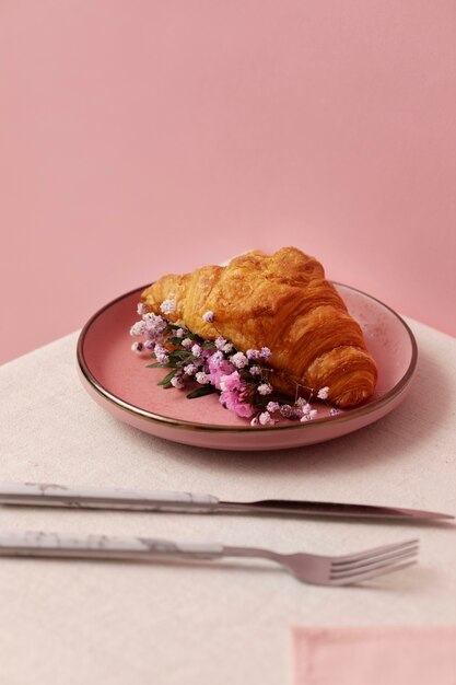 Croissant de alto ángulo y flores en un plato