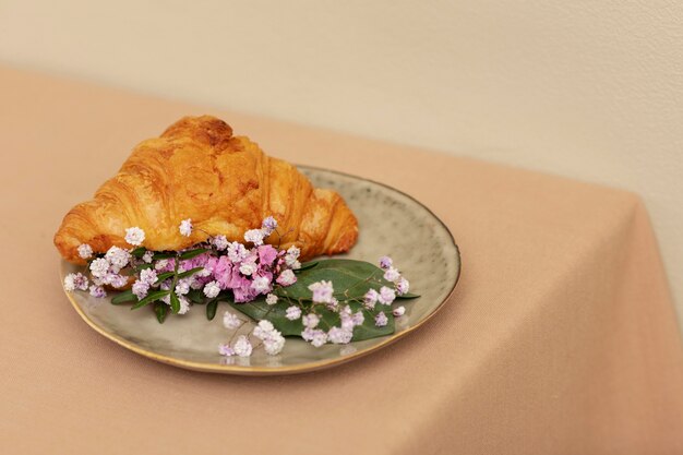 Croissant de alto ángulo y flores en un plato