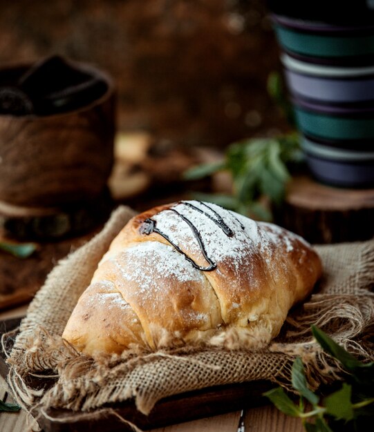 Croissant de chocolate adornado con azúcar en polvo y jarabe de azúcar