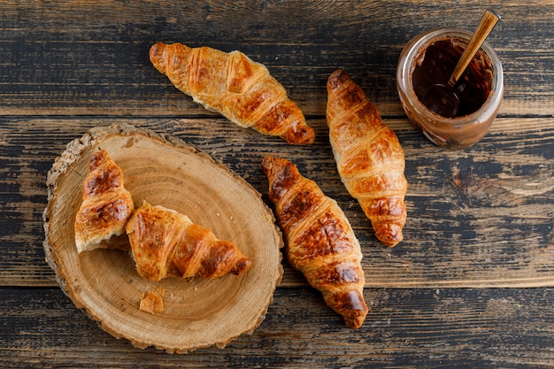 Croissant con crema de chocolate plano sobre tabla de madera y corte