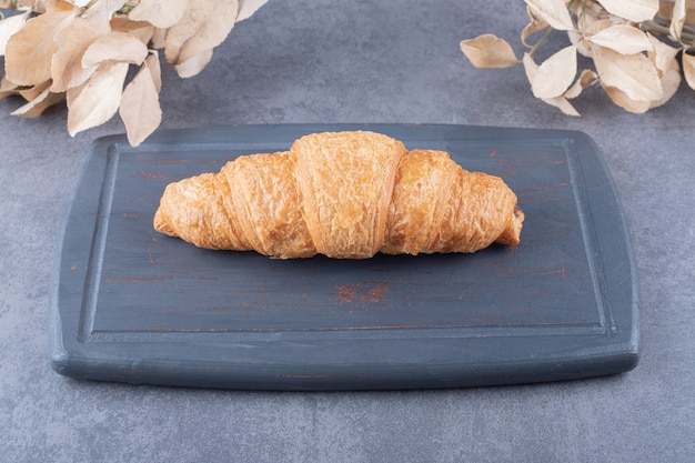 Croissant francés fresco casero sobre plancha de madera gris.