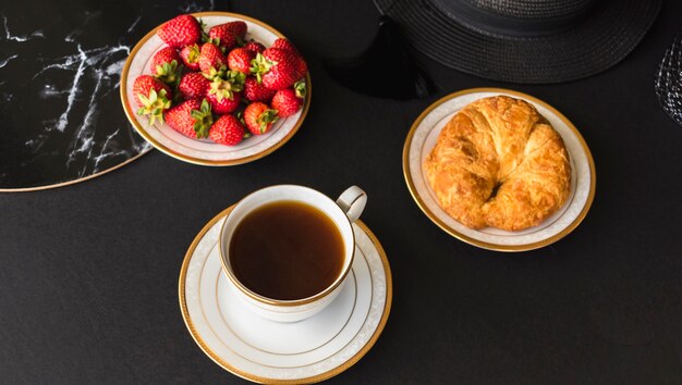 Croissant y fresas con té en la mesa