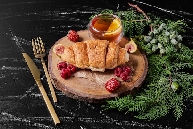 Croissant con frutos rojos en bandeja de madera.