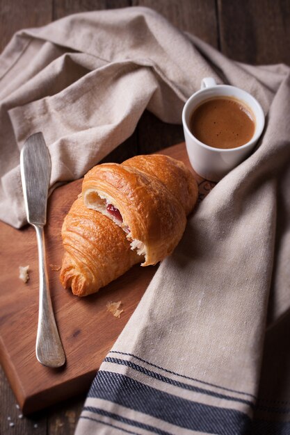 Croissant junto a un cuchillo y una taza de café