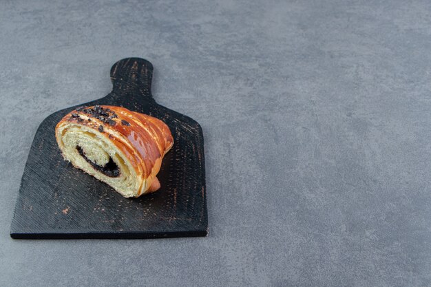 Croissant medio cortado con chocolate en tablero negro.