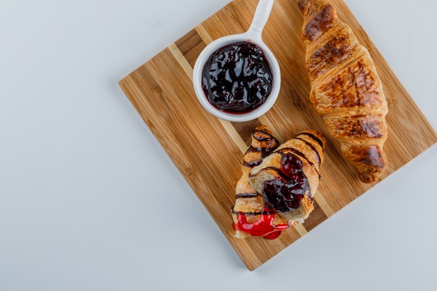 Croissant con mermelada plana en blanco y tabla de cortar