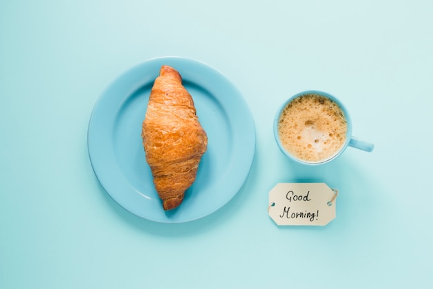 Croissant plano en plato con café