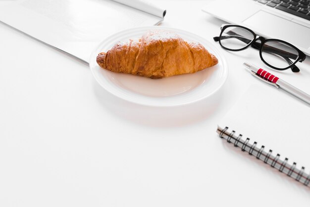 Croissant en un plato cerca del cuaderno