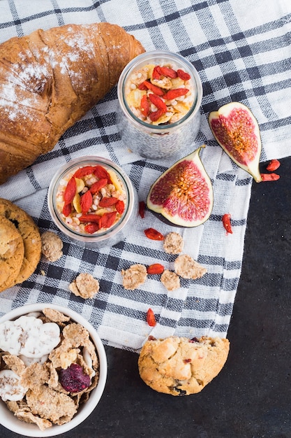 Foto gratuita croissant recién hecho galleta; copos de maíz; budín de semillas de chía y rodajas de higo sobre tela