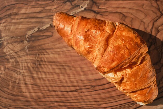 Croissant recién horneado en una mesa de madera idea de desayuno francés día soleado y brillante Vista superior plana con espacio de copia para texto