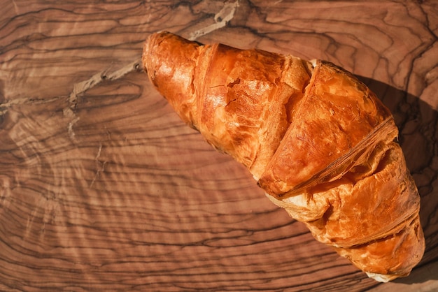 Croissant recién horneado en una mesa de madera idea de desayuno francés día soleado y brillante Vista superior plana con espacio de copia para texto