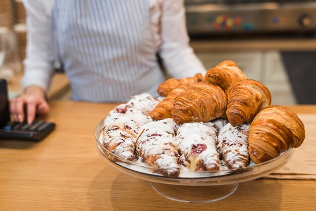 Croissant recién horneado en soporte de pastel en el mostrador de la cafetería