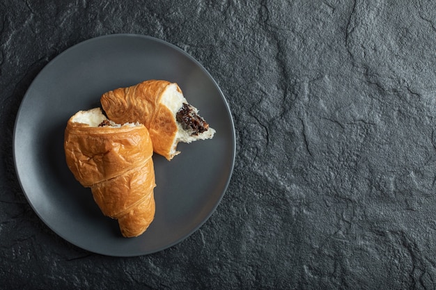 Croissant relleno de chocolate sobre un fondo oscuro.