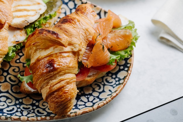 Croissant sandwich con salmón ahumado y verduras.