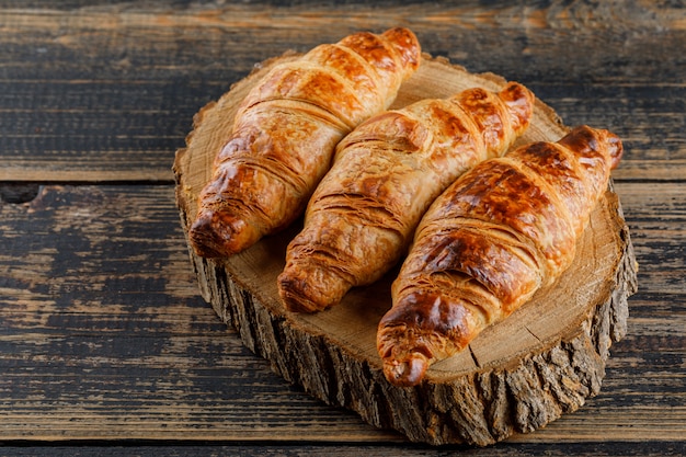 Croissant en tabla de cortar y madera. Vista de ángulo alto.