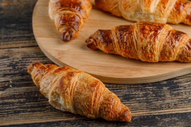 Croissant en la tabla de madera y de corte, primer.