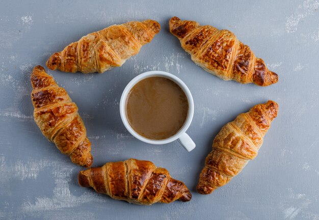 Croissant con taza de café, plano.