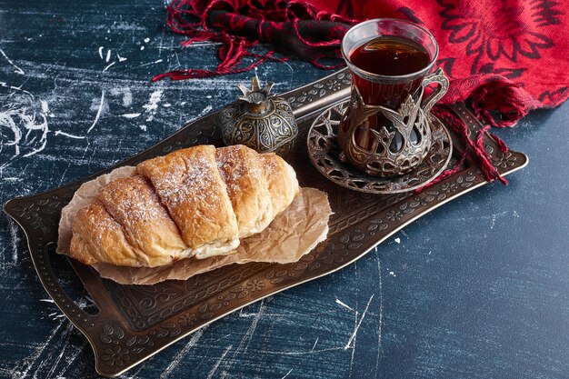 Un croissant con un vaso de té.