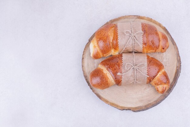 Croissants aislado en una bandeja de madera sobre superficie gris