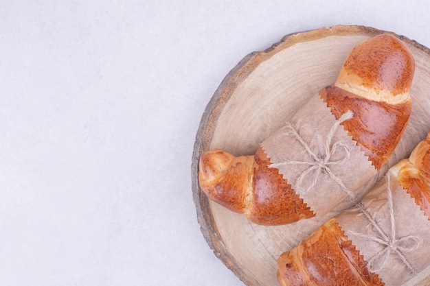 Foto gratuita croissants aislado en una bandeja de madera sobre superficie gris