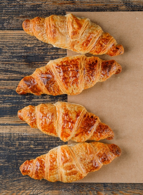 Foto gratuita croissants en bolsa de madera y papel. aplanada